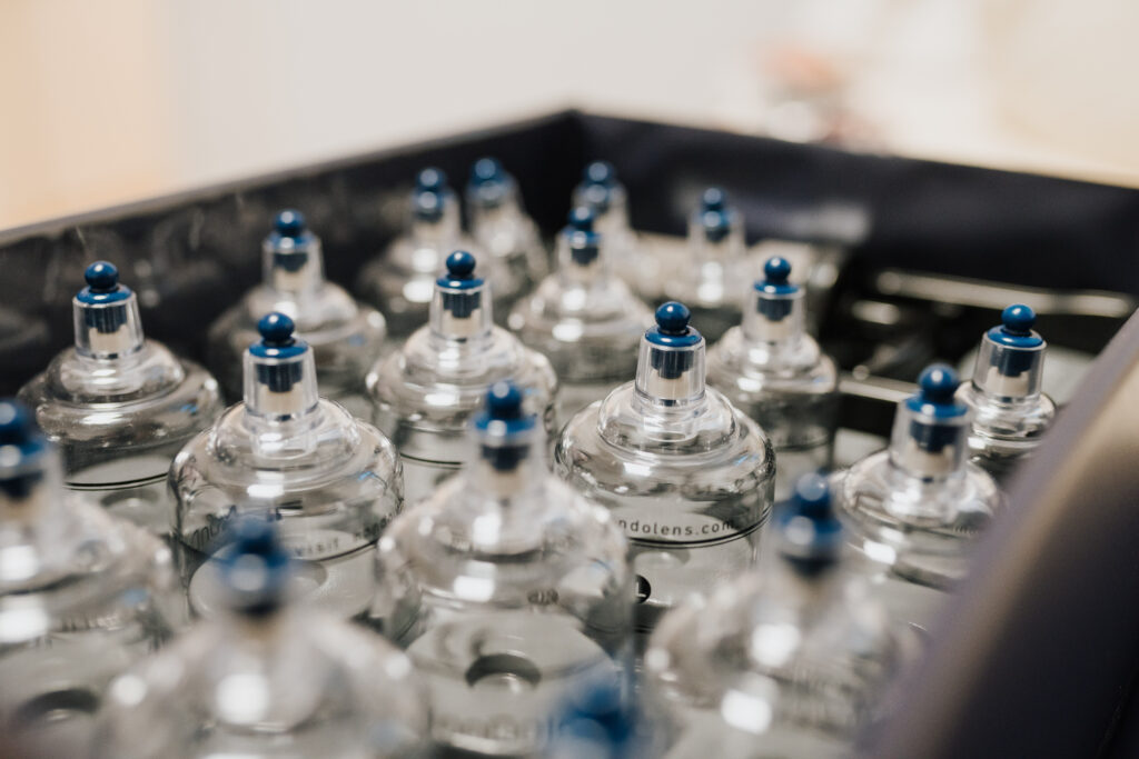 Eine Nahaufnahme mehrerer Klarglasflaschen mit blauen Verschlüssen, die in einem schwarzen Behälter in der Neurologischen Therapie Wolfenbüttel aufgereiht sind.